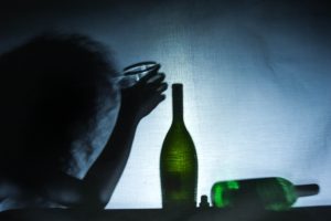 człowiek uzależniony od alkoholu z butelką wina